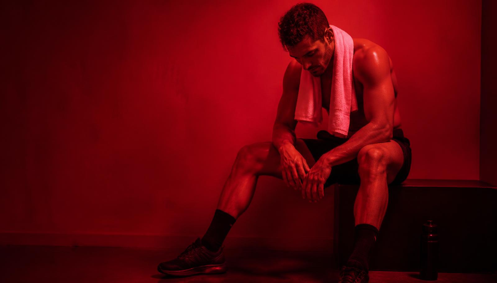 Athlete resting after training in a studio bathed in deep red light
